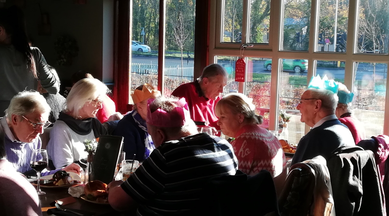 Members of the branch and their carers enjoying Xmas lunch. Sat in front of sunny windows.