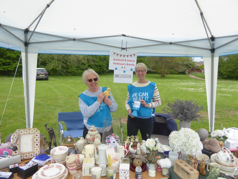 A gazebo is above a table piled high with bric-a-brac. Wendy and Yvette are manning the stall.