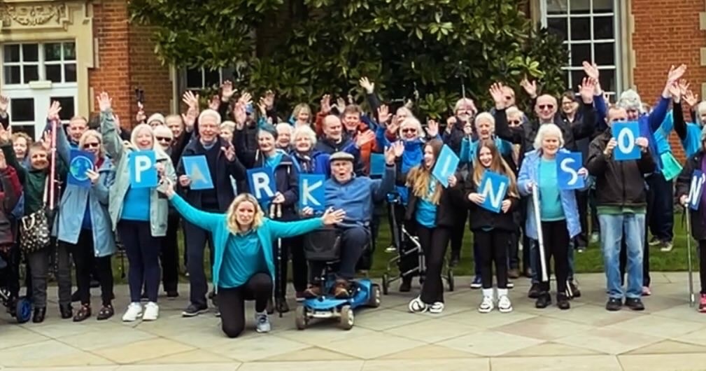 Large group of people with some holding letters that spell PARKINSON